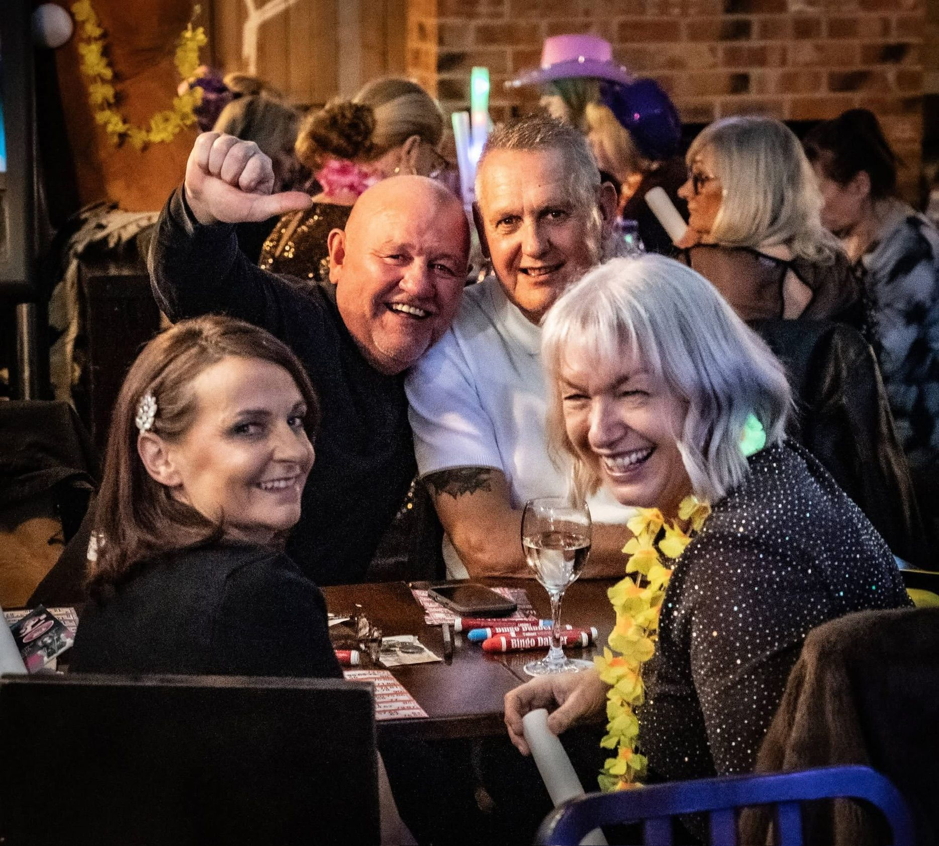 Four guests laughing at a table with bingo dabbers and glow sticks during Bonkers Bingo at The Bridge Hotel & Spa